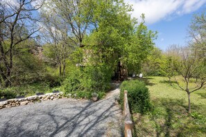 A gravel path leading to a stone building surrounded by trees and greenery.