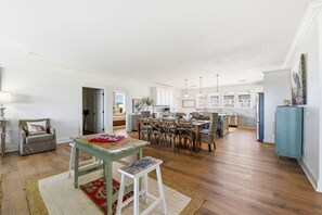 A spacious living area with a dining table, chairs, and a kitchen in the background. - Welcome to Oyster Bay Escape! (St. George Island)