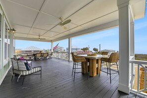 A covered outdoor deck with a table and chairs, a flag, and a view of the ocean. - Welcome to Oyster Bay Escape! (St. George Island)