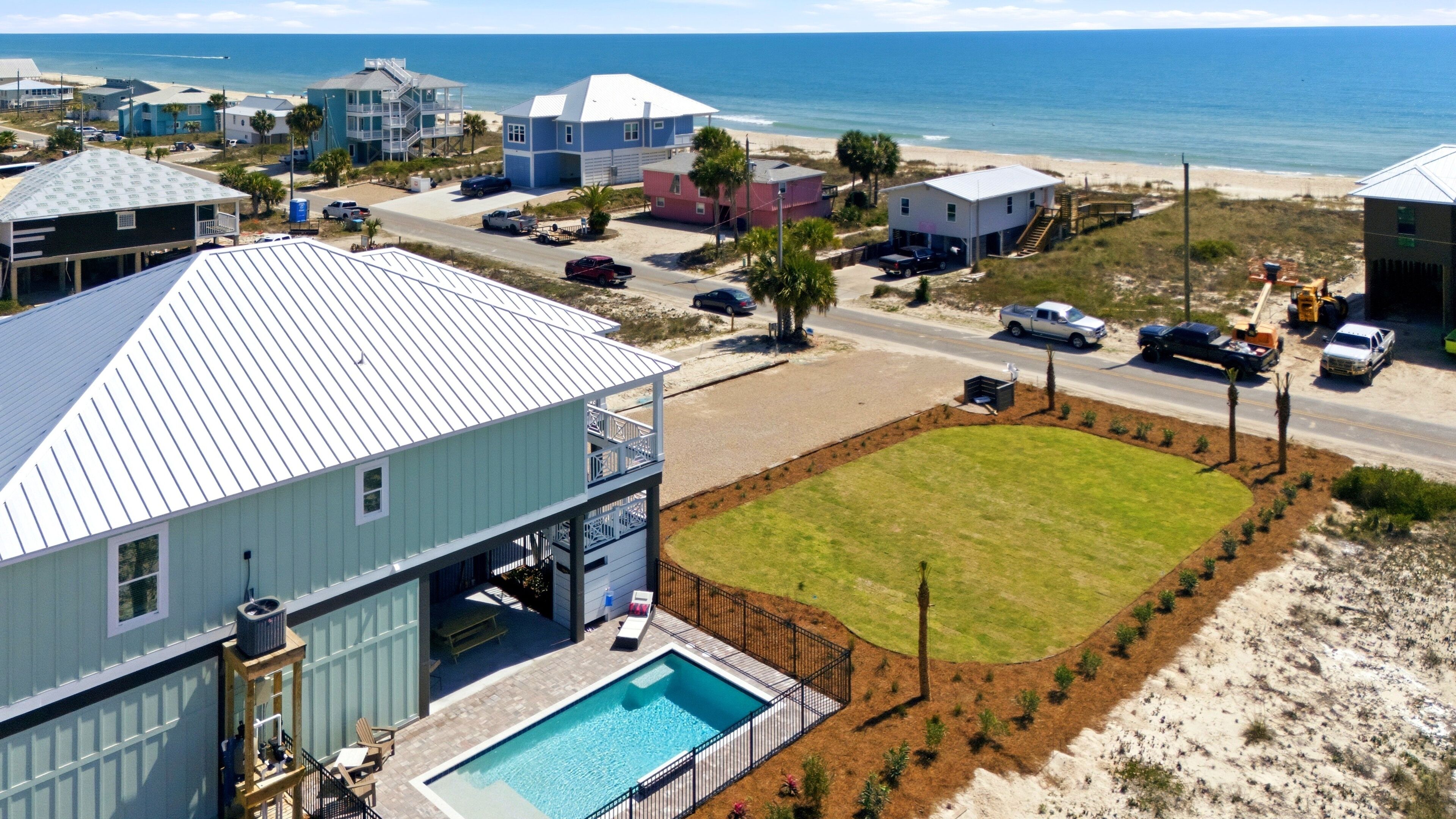 A residential area with a swimming pool, a large lawn, and a view of the ocean.