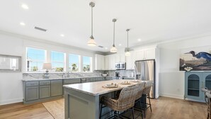 Una cocina amplia con una isla grande, iluminación colgante y vistas al exterior.