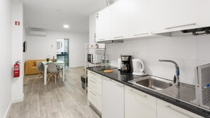 Uma cozinha moderna com armários brancos, uma pia de aço inoxidável e uma cafeteira.