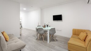 Uma sala de estar moderna com um sofá, uma mesa de centro e uma TV fixada na parede.
