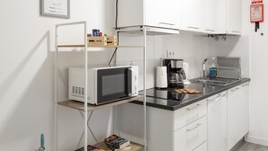 Uma cozinha moderna com armários brancos, micro-ondas, cafeteira e pia.