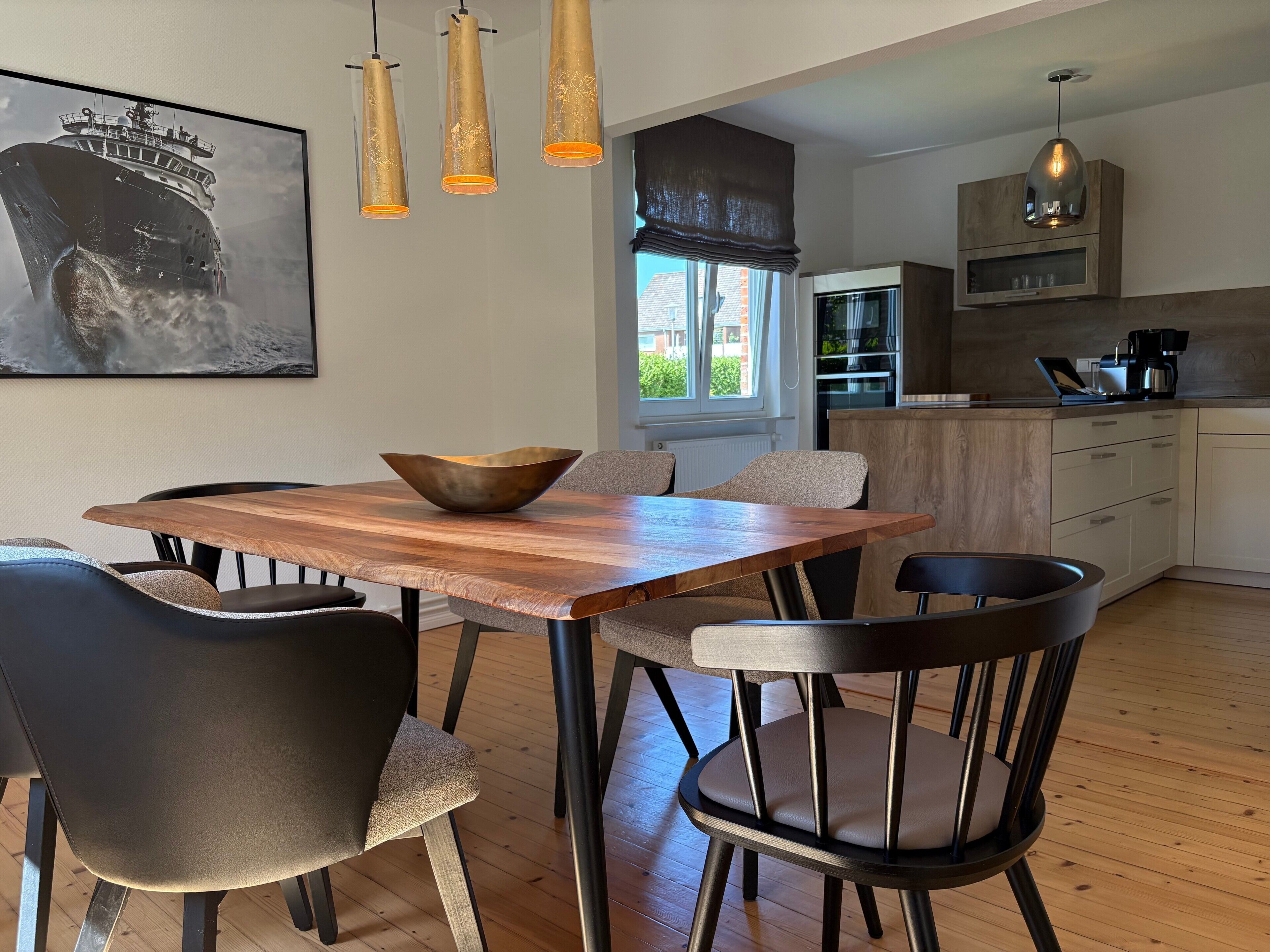 A modern kitchen with wooden cabinets, a coffee machine, and a window with a view.