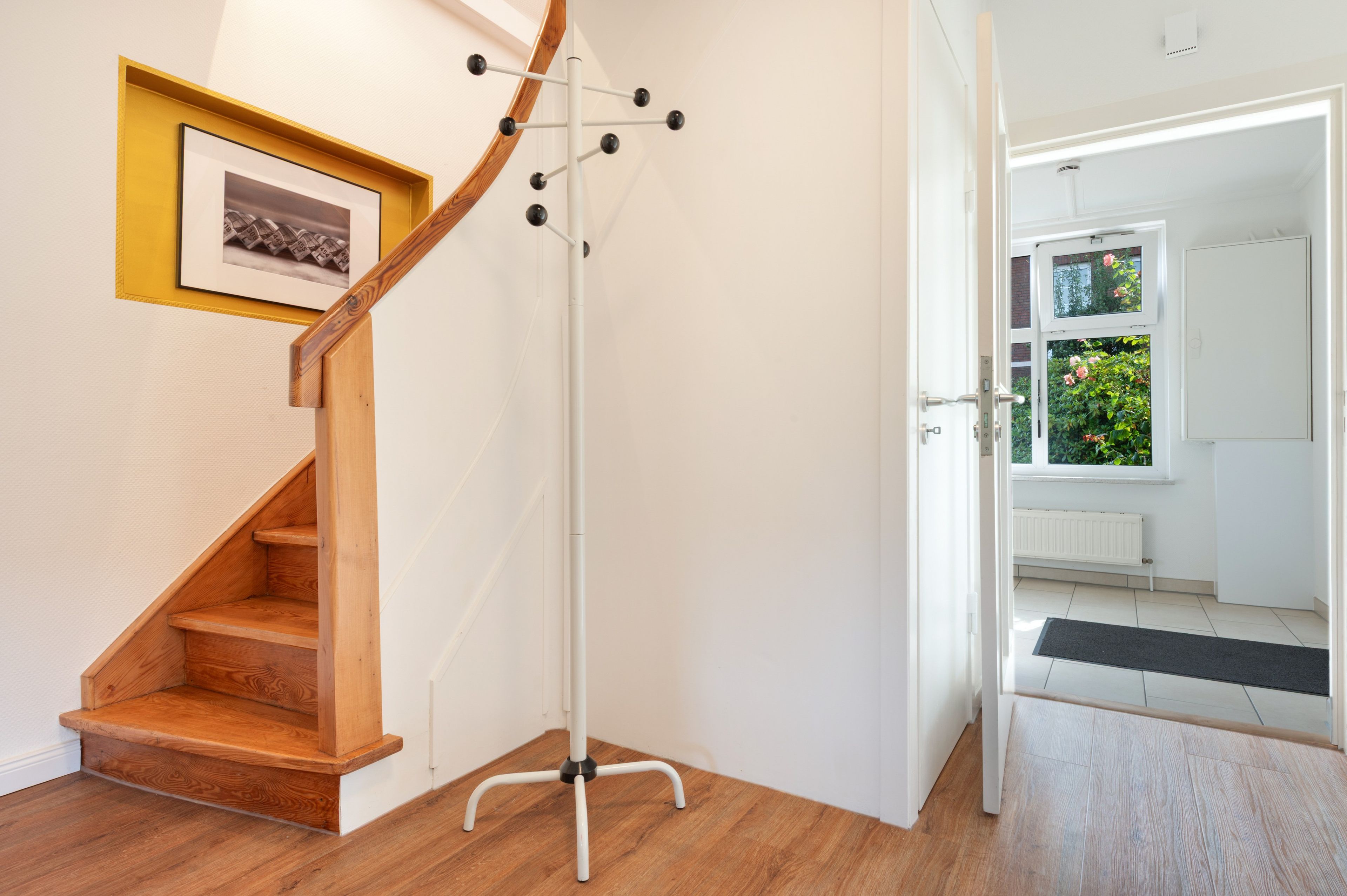 Un escalier en bois menant à un palier où se trouve un porte-manteau.