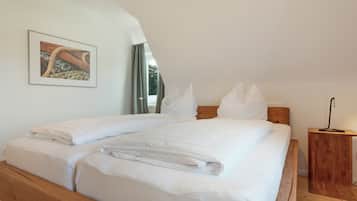 A neatly made double bed with white linens, a wooden headboard, and a small bedside table with a lamp.