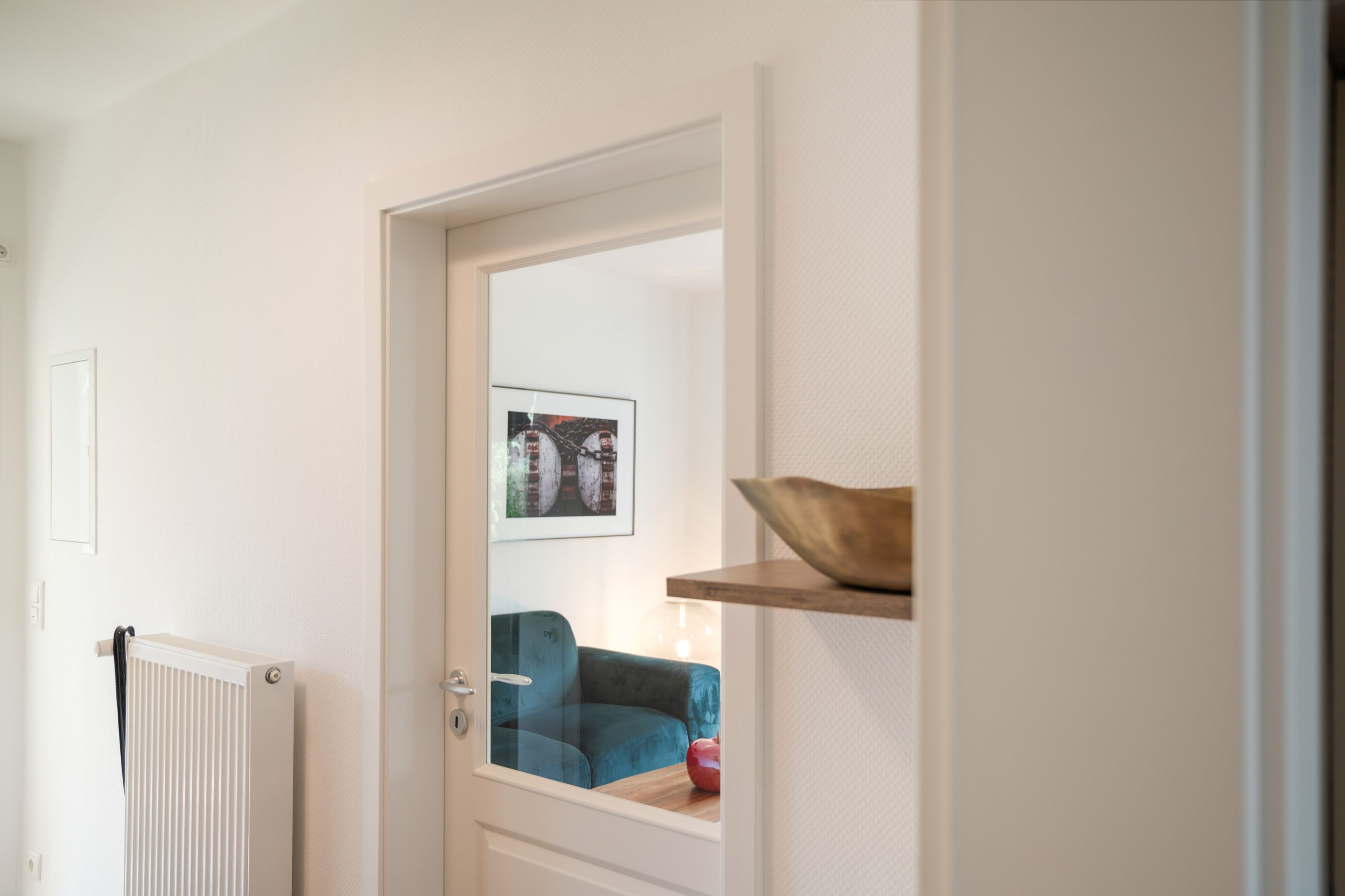 A doorway leading to a room with a radiator, a blue sofa, and a framed picture on the wall.
