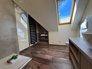 Ein modernes Badezimmer mit Dachfenster, Holzboden und Handtuchhalter.