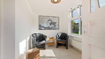 A modern room with two leather chairs, a wooden table, a framed picture on the wall, and a window with a view of greenery.