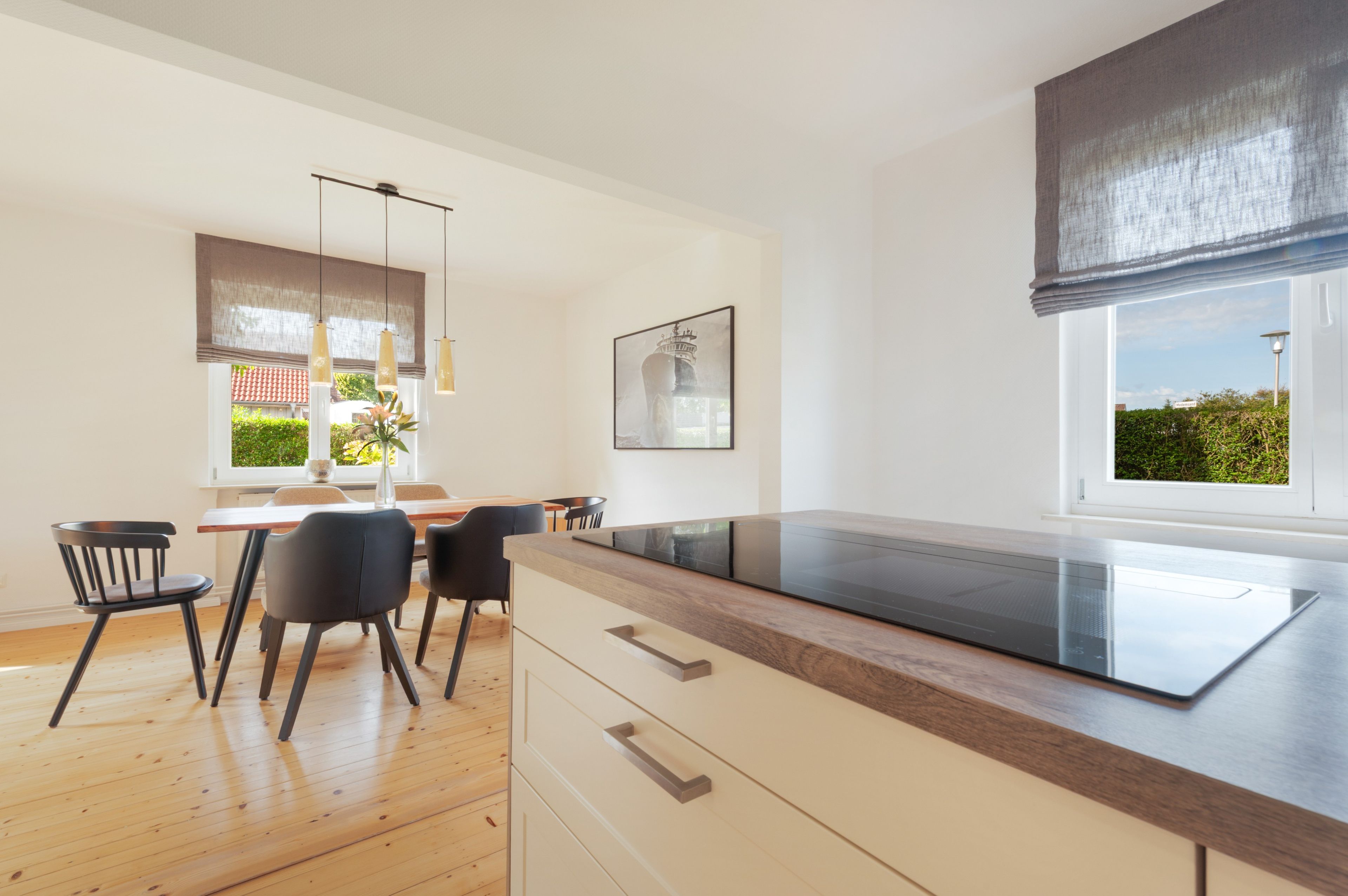 Een moderne keuken met een inbouwoven, houten vloeren en een eethoek met stoelen en een tafel.
