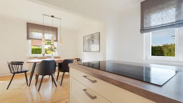 Een moderne keuken met een inbouwoven, houten vloeren en een eethoek met stoelen en een tafel.