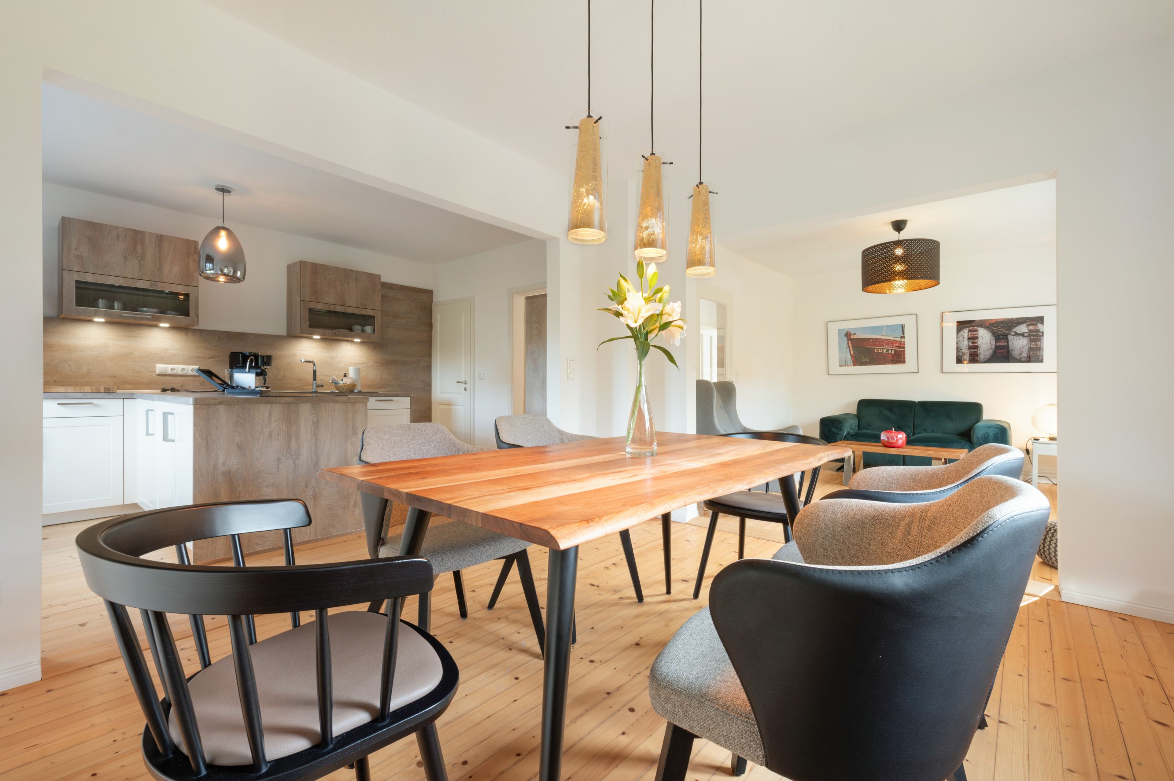 Una cocina moderna con armarios de madera, una mesa de comedor con sillas e iluminación colgante.