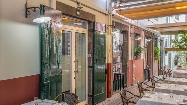 An outdoor dining area with tables and chairs, a green door, and a number '10' sign. - Tanoeiros Studio - Spacious and Comfortable Accommodation (Funchal)