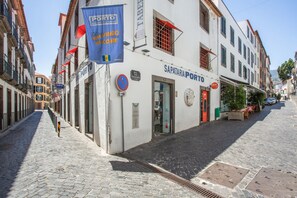 Een straat met een gebouw waarop 'SAPATARIA PORTO' staat en een blauwe banner.