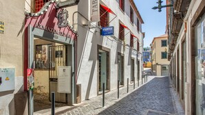 A cobblestone street with a restaurant named 'Armação do Sal' and a blue sign for 'Porto.' - Tanoeiros Studio - Spacious and Comfortable Accommodation (Funchal)