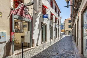 A cobblestone street with a restaurant named 'Armação do Sal' and a blue sign for 'Porto.' - Tanoeiros Studio - Spacious and Comfortable Accommodation (Funchal)