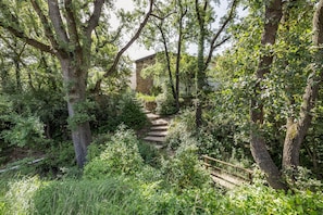 A stone staircase leading to a building surrounded by dense greenery and trees. - Eco Masias Cal Ferran Country House with Mountain Views, Wi-Fi, and Air Conditioning (El Bruc)