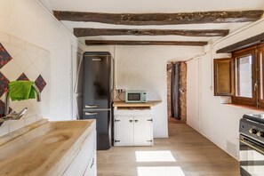 Een kleine keuken met een koelkast, magnetron en fornuis.