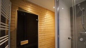 Ein modernes Badezimmer mit einer Wandpaneelausstattung aus Holz, einer Duschkabine aus Glas und einer Tür mit Griff.