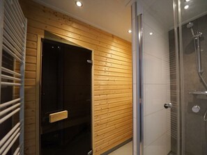 Ein modernes Badezimmer mit einer Wandpaneelausstattung aus Holz, einer Duschkabine aus Glas und einer Tür mit Griff.