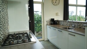 Eine moderne Küche mit Gasherd, Kaffeemaschine, Spüle und einer Uhr an der Wand.
