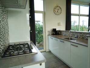 Eine moderne Küche mit Gasherd, Kaffeemaschine, Spüle und einer Uhr an der Wand.