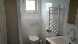 Ein Badezimmer mit Toilette, Waschbecken, Handtuchhalter und einem Fenster.