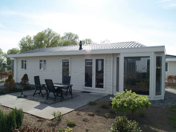A single-story house with a patio, a dining table with chairs, and a small garden area. - Holiday Home in Dordrecht With Terrace (Dordrecht)