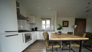 Eine moderne Küche mit weißen Schränken, einem Holztisch und einem eingebauten Backofen.