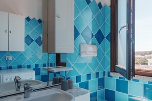 Ein Badezimmer mit Waschbecken, Spiegel und blauen Fliesenwänden.