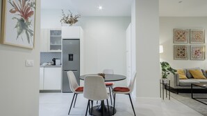 A modern kitchen with a refrigerator, dining table, and chairs.