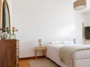 Quarto com cama, mesas de cabeceira, um espelho e um abajur.