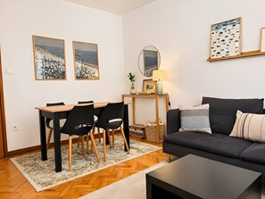 Ein modernes Wohnzimmer mit Essbereich, einer Couch, einem Couchtisch und Kunstwerken an den Wänden.