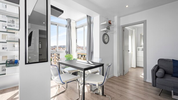 A modern apartment with a dining area, a living room, and a view of the city.
