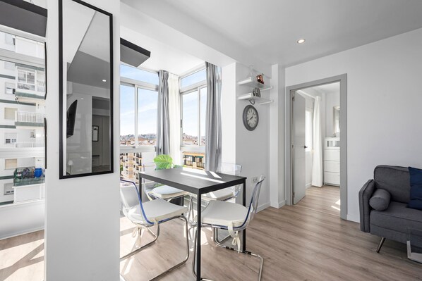 A modern apartment with a dining area, a living room, and a view of the city.