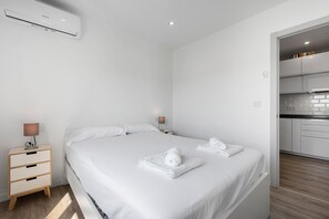 A modern hotel room with a large bed, bedside tables, a lamp, and a view into the kitchen. - Apartment 'Copenhague - 049' with Mountain Views, Wi-Fi, and Air Conditioning (Torre del Mar)