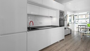 A modern kitchen with white cabinetry, a black countertop, a red faucet, and a built-in oven. - Apartment 'Copenhague - 049' with Mountain Views, Wi-Fi, and Air Conditioning (Torre del Mar)