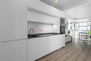 Eine moderne Küche mit weißen Schränken, einer schwarzen Arbeitsplatte, einem roten Wasserhahn und einem eingebauten Backofen.