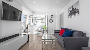 A modern living room with a sofa, a coffee table, a TV, and a dining area with a table and chairs. - Apartment 'Copenhague - 049' with Mountain Views, Wi-Fi, and Air Conditioning (Torre del Mar)