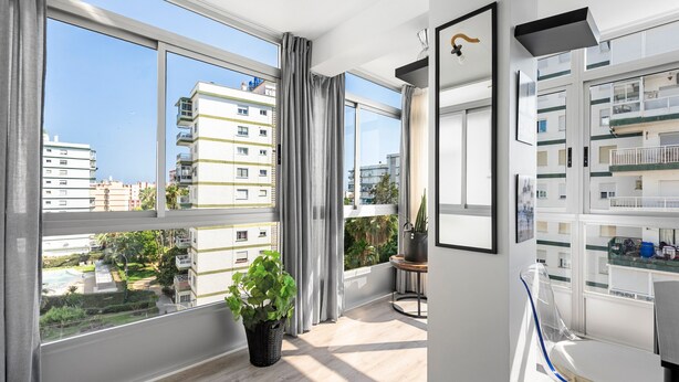 A modern apartment with large windows, a potted plant, and a view of neighboring buildings. - Apartment 'Copenhague - 049' with Mountain Views, Wi-Fi, and Air Conditioning (Torre del Mar)
