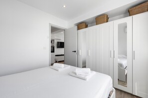 Una habitación de hotel moderna con una cama grande, un armario y un baño visible a través de una puerta abierta.