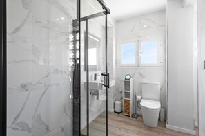 Un baño moderno con cabina de ducha de vidrio, inodoro y lavamanos.