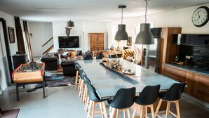 Eine moderne Küche mit einer großen Kochinsel, Barhocker, einem Tischfußballtisch und einem Essbereich mit einer Couch und Sesseln.