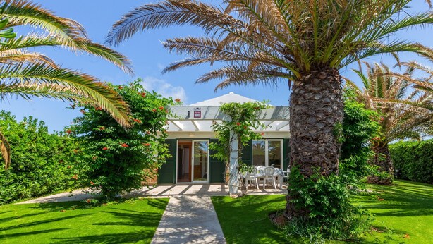 A building with a stone pillar, a paved pathway, and a well-maintained lawn. - Holiday Home 'Villa Jaume' with Private Pool, Private Garden and Air Conditioning (Cap d'Artrutx)