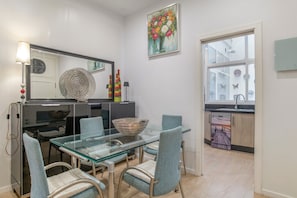 Een moderne keuken met een glazen eettafel, stoelen en een grote spiegel.