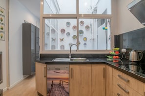 Een moderne keuken met een groot raam, houten kastjes, een vaatwasser en een koffiezetapparaat.