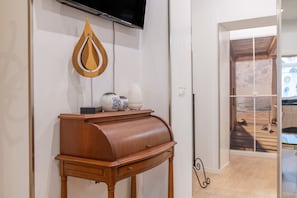 Een kamer met een houten tafel, een televisie en een decoratief object aan de muur.