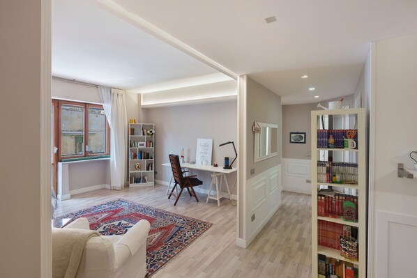 A modern living room with a large window, a desk, and a bookshelf.