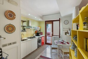 Uma cozinha compacta com máquina de lavar, área de refeições com mesa e cadeiras, e um armário amarelo.